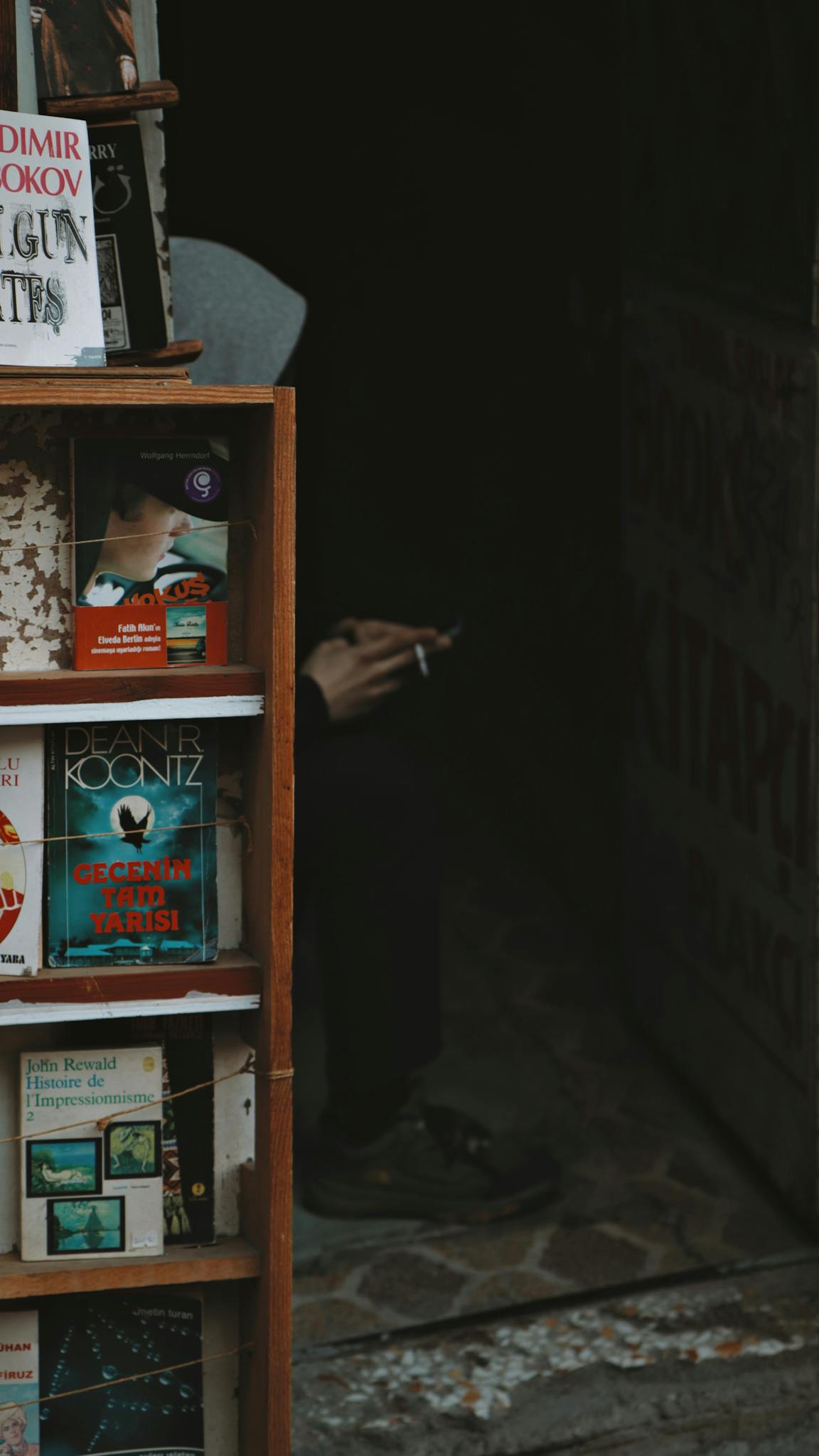 An inviting street bookstall with a smoker, displaying various books for sale.